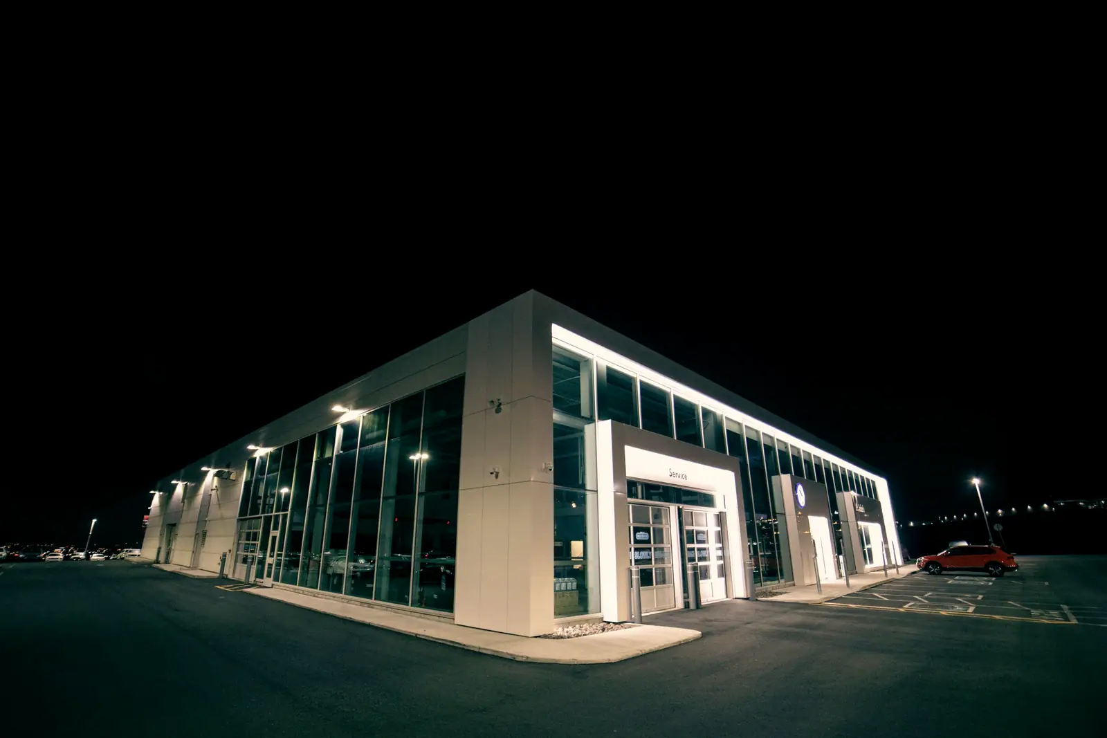A modern vehicle dealership lit up at night