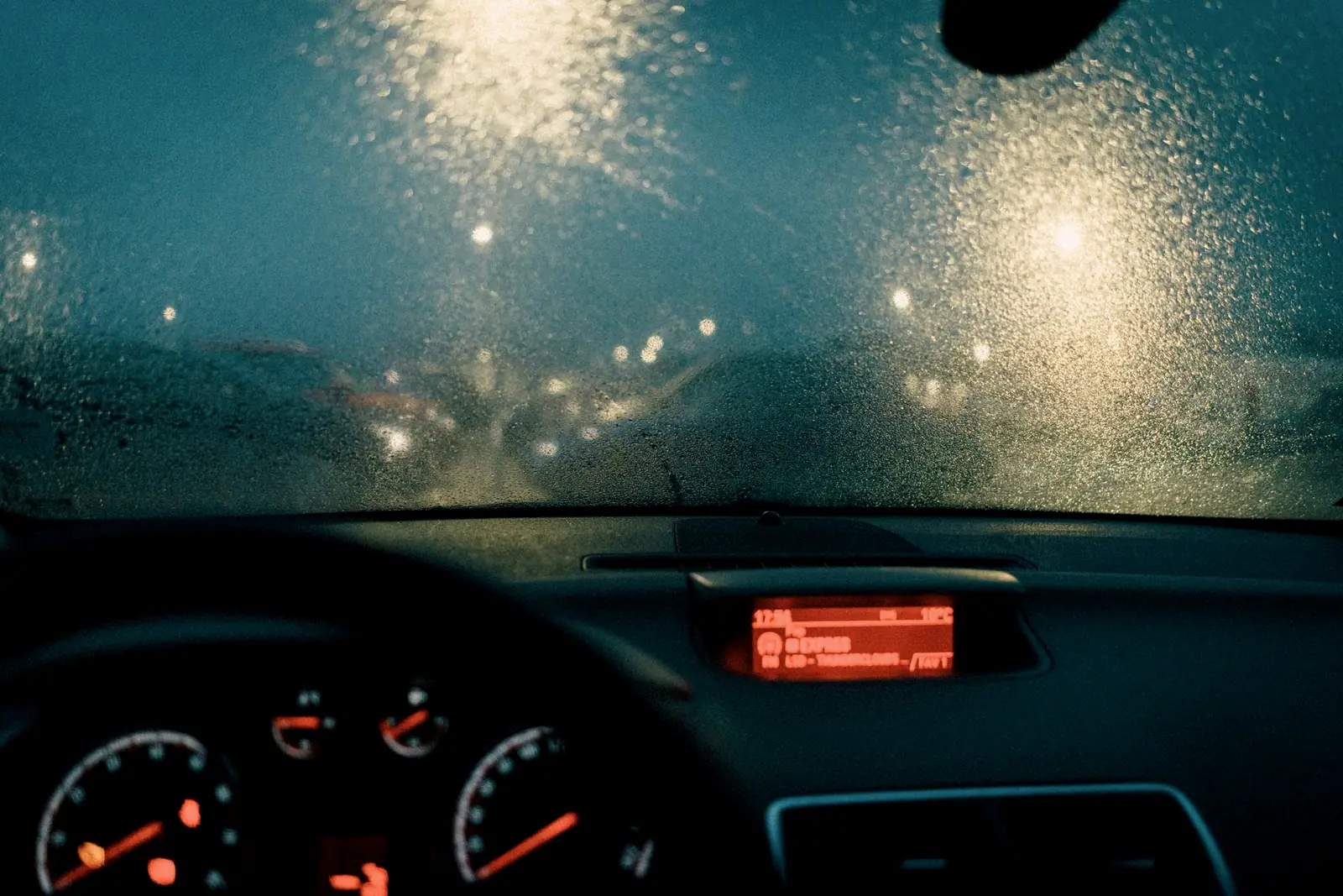 Rain on a windshield at night, dashboard lights glowing